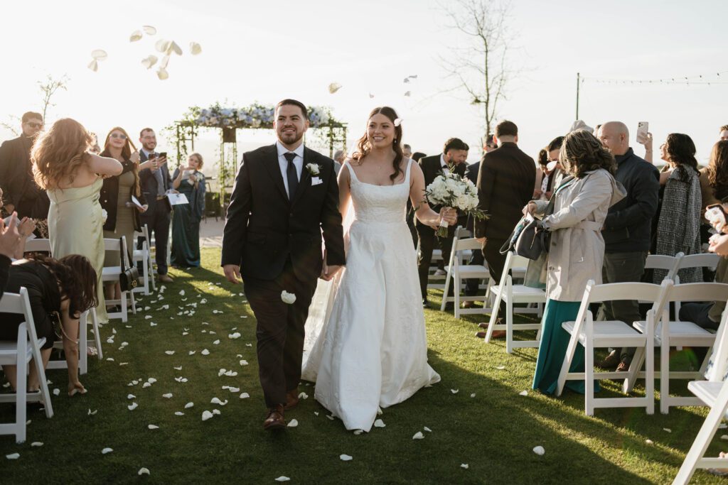 California bride and groom walking down outdoor wedding aisle with guests cheering